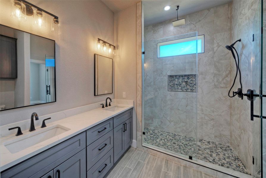 Custom tile work highlights a spacious walk-in shower alongside a dual-sink vanity. Custom tile work highlights a spacious walk-in shower alongside a dual-sink vanity.