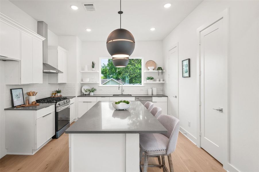 The stunning kitchen pairs sleek quartz surfaces with dramatic designer lighting and a large picture window hat fills the space with natural light.