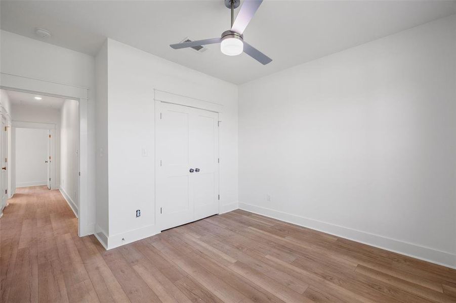 Room featuring wood-finish flooring, white walls, and a contemporary ceiling fan