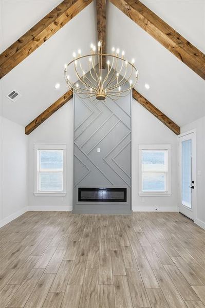 Unfurnished living room with a chandelier, light wood-style flooring, plenty of natural light, and recessed lighting