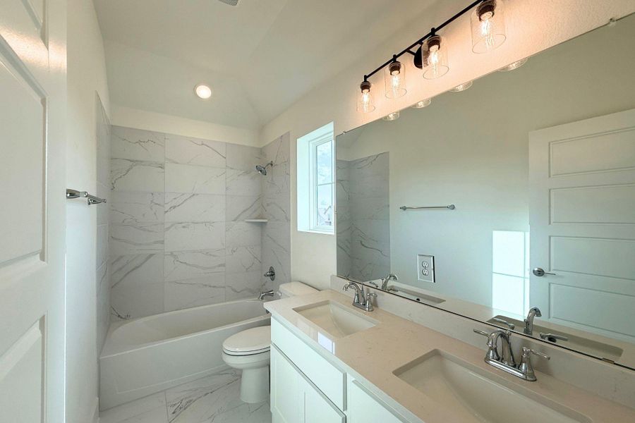A well-lit bathroom with dual sinks and a sleek shower-tub combination. A well-lit bathroom with dual sinks and a sleek shower-tub combination.