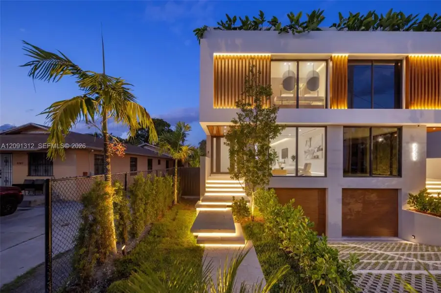 Modern architectural exterior featuring a stucco facade, vertical wood-slat accents, floor-to-ceiling glass windows, integrated staircase lighting, and a permeable paver driveway Modern architectural exterior featuring a stucco facade, vertical wood-slat accents, floor-to-ceiling glass windows, integrated staircase lighting, and a permeable paver driveway