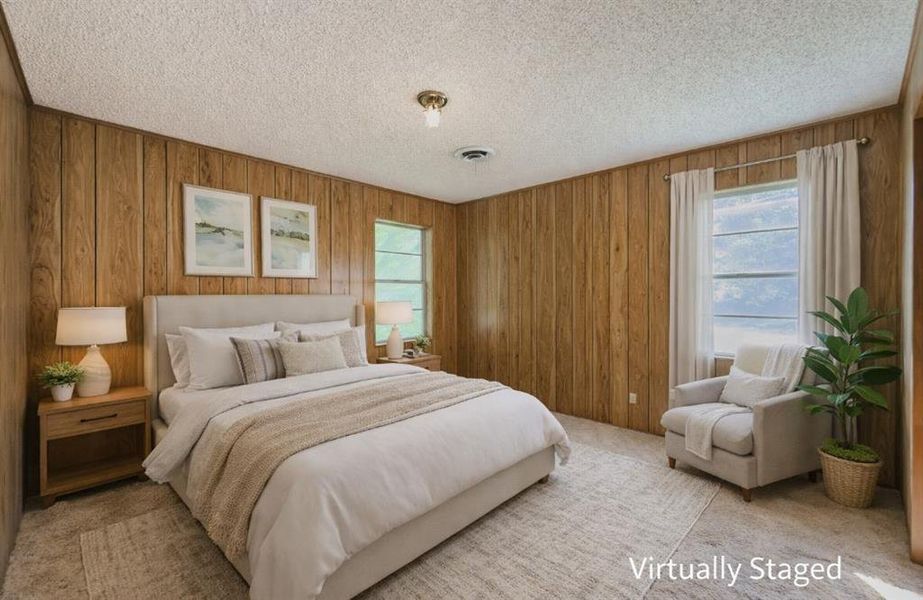 Bedroom featuring light carpet, wooden walls, and a textured ceiling