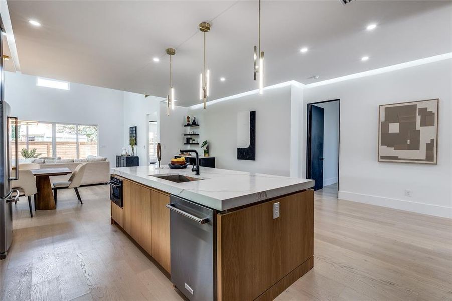 Kitchen featuring hanging light fixtures, sink, a center island with sink, and light hardwood / wood-style flooring