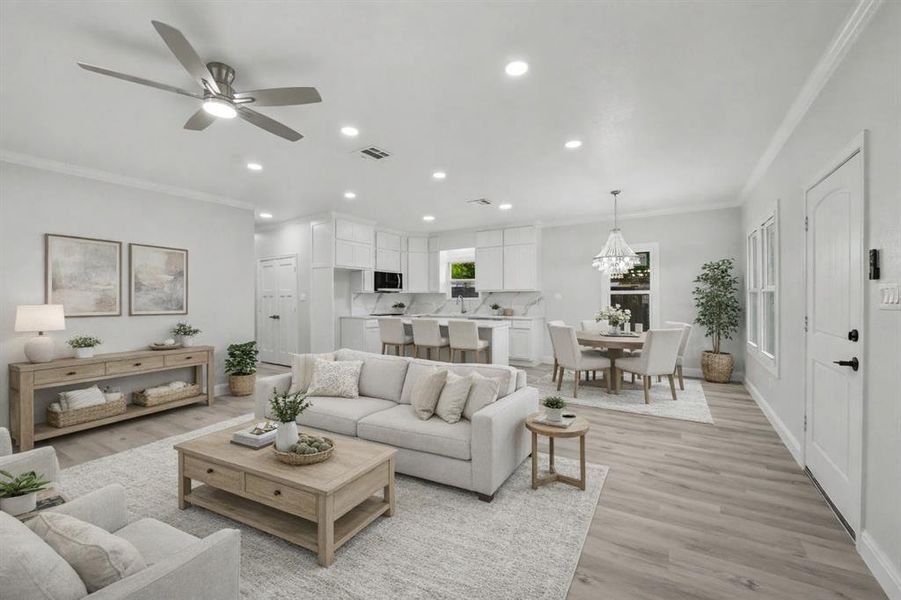 Open-concept living area featuring light wood-finish flooring, recessed lighting, a contemporary ceiling fan, a kitchen island with seating, and a dining area with a chandelier