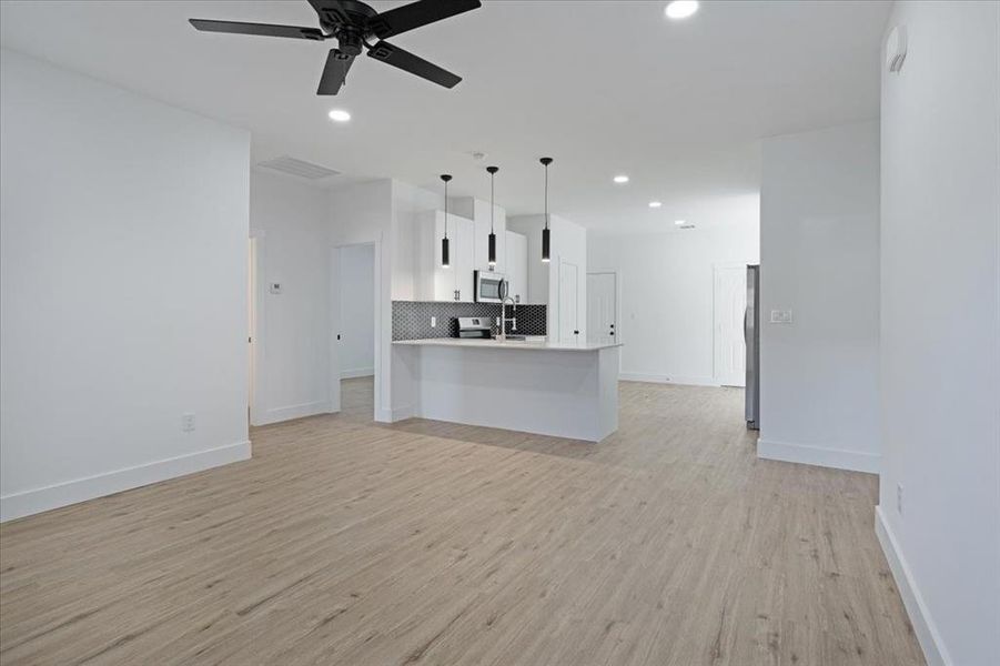 Unfurnished living room featuring ceiling fan, sink, and light hardwood / wood-style floors