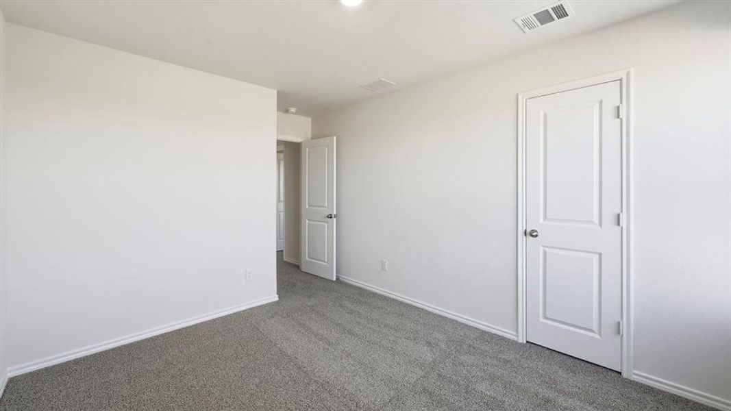 Unfurnished bedroom with carpet flooring and baseboards Unfurnished bedroom with carpet flooring and baseboards