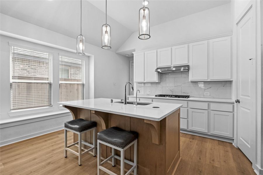 This modern kitchen features sleek white cabinets, a large island with a sink, and stylish pendant lighting. It has a bright, open feel with natural light from large windows and is complemented by hardwood floors and stainless steel appliances. This modern kitchen features sleek white cabinets, a large island with a sink, and stylish pendant lighting. It has a bright, open feel with natural light from large windows and is complemented by hardwood floors and stainless steel appliances.