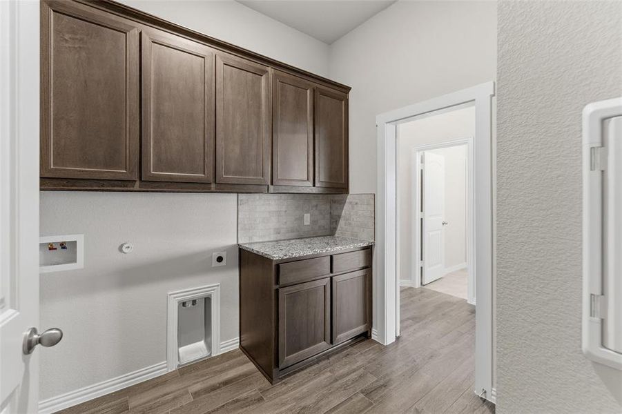 Laundry room with cabinet space, light wood finished floors, a textured wall, washer hookup, and electric dryer hookup