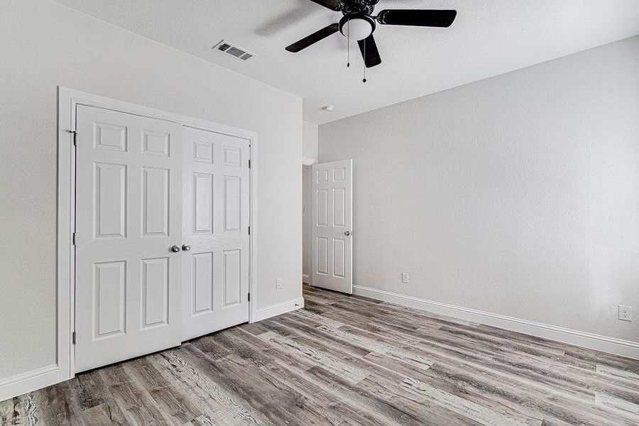 bedroom 3 featuring ceiling fan, hardwood / wood-style flooring, and a closet