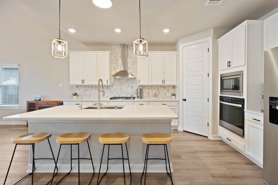 This modern kitchen features a spacious island with seating for four, sleek white cabinetry, stainless steel appliances, and elegant pendant lighting, all set against a backdrop of light wood flooring and a tasteful backsplash. Home includes water filtration system for the perfect drinking water from your sink and refrigerator. This modern kitchen features a spacious island with seating for four, sleek white cabinetry, stainless steel appliances, and elegant pendant lighting, all set against a backdrop of light wood flooring and a tasteful backsplash. Home includes water filtration system for the perfect drinking water from your sink and refrigerator.