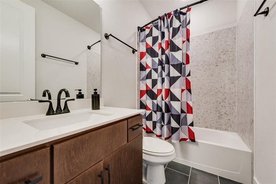 Bathroom with shower / tub combo, vanity, and dark tile patterned flooring