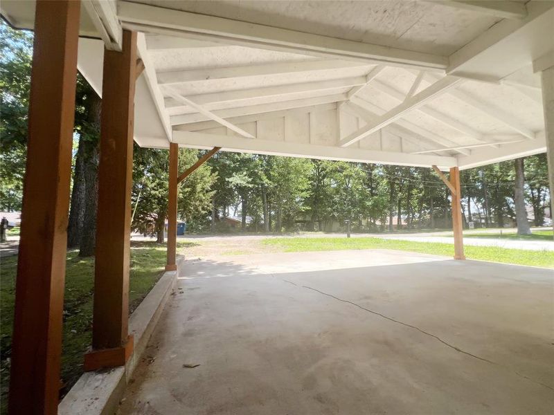 Covered concrete patio featuring a white painted ceiling, exposed rafters, and wood support beams