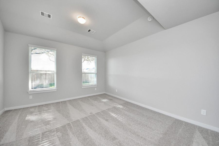 Escape to tranquility in this spacious primary room, adorned with plush carpeting and bathed in the soothing hues of warm paint colors, creating a cozy retreat for relaxation. Sample photo of completed home with similar floor plan. Actual colors and selections may vary.