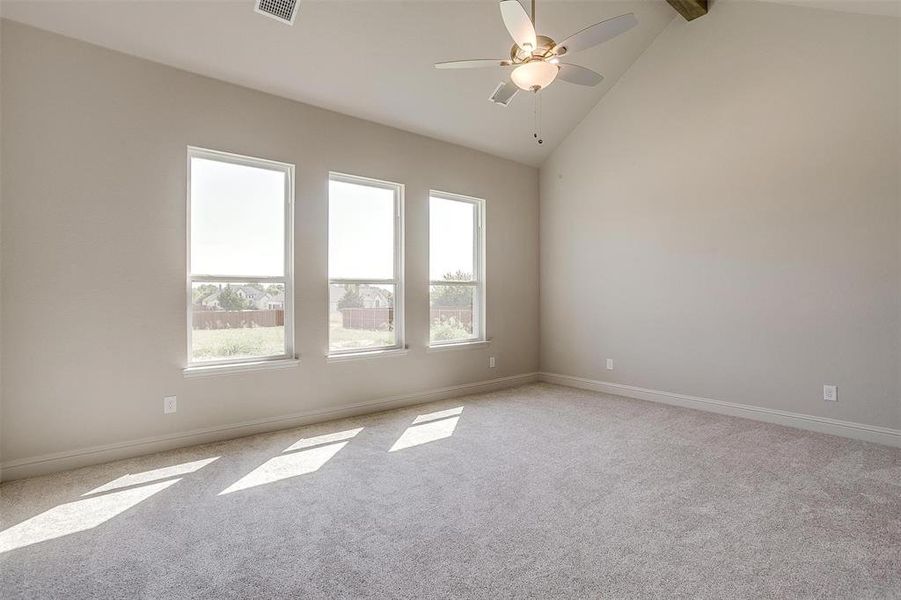 Unfurnished room featuring ceiling fan, vaulted ceiling with beams, and light colored carpet