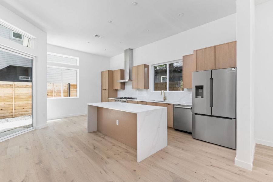 Kitchen with a center island, appliances with stainless steel finishes, light countertops, light wood-style floors, and modern cabinets Kitchen with a center island, appliances with stainless steel finishes, light countertops, light wood-style floors, and modern cabinets