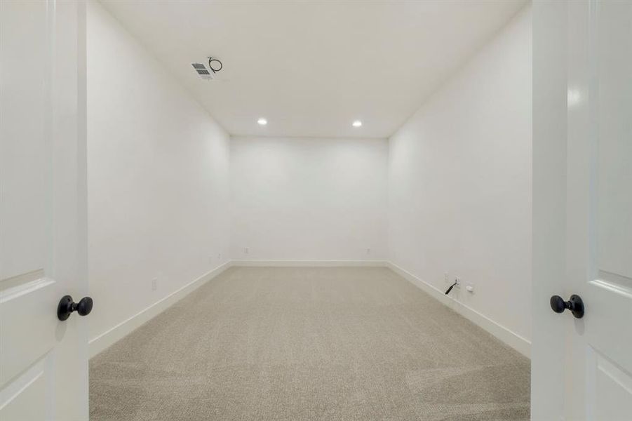 Recessed lighting illuminates this room featuring light-toned carpeting and crisp white walls Recessed lighting illuminates this room featuring light-toned carpeting and crisp white walls