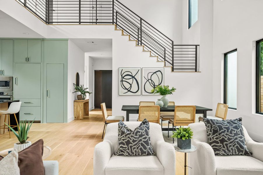 Bright, airy living space boasts a grand staircase, sleek kitchen, and abundant natural light. Bright, airy living space boasts a grand staircase, sleek kitchen, and abundant natural light.