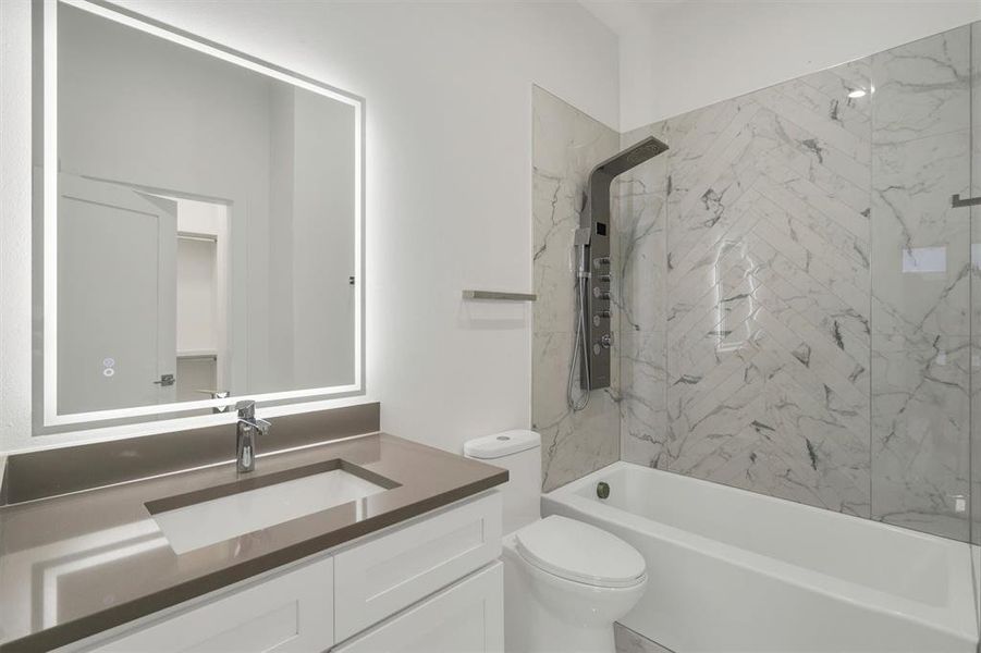 Full bathroom featuring vanity, tiled shower / bath combo, and toilet