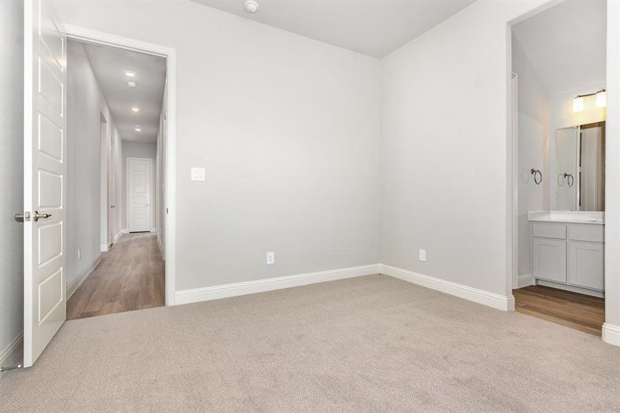 Unfurnished bedroom with light colored carpet, ensuite bath, and recessed lighting