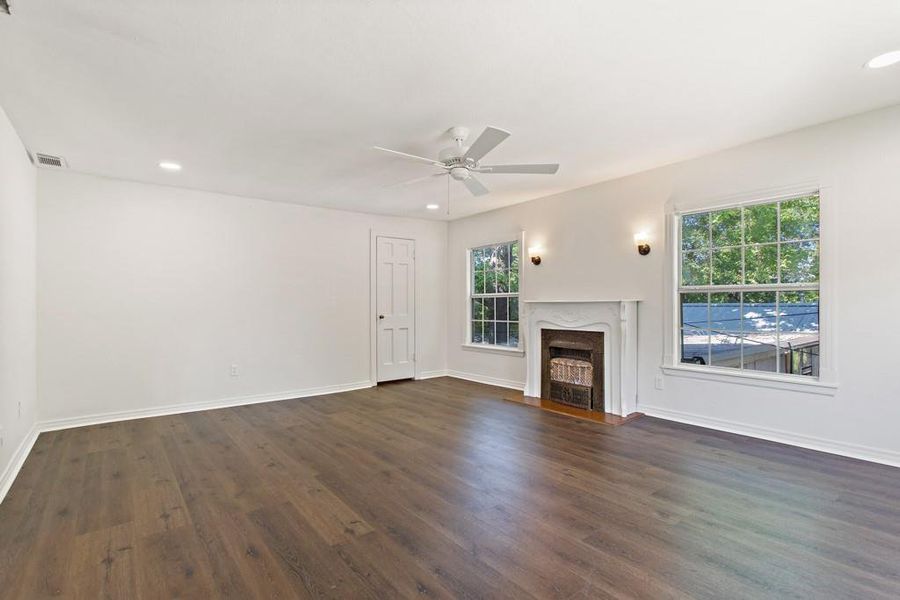 Unfurnished living room featuring a premium fireplace, plenty of natural light, dark wood-style floors, and recessed lighting