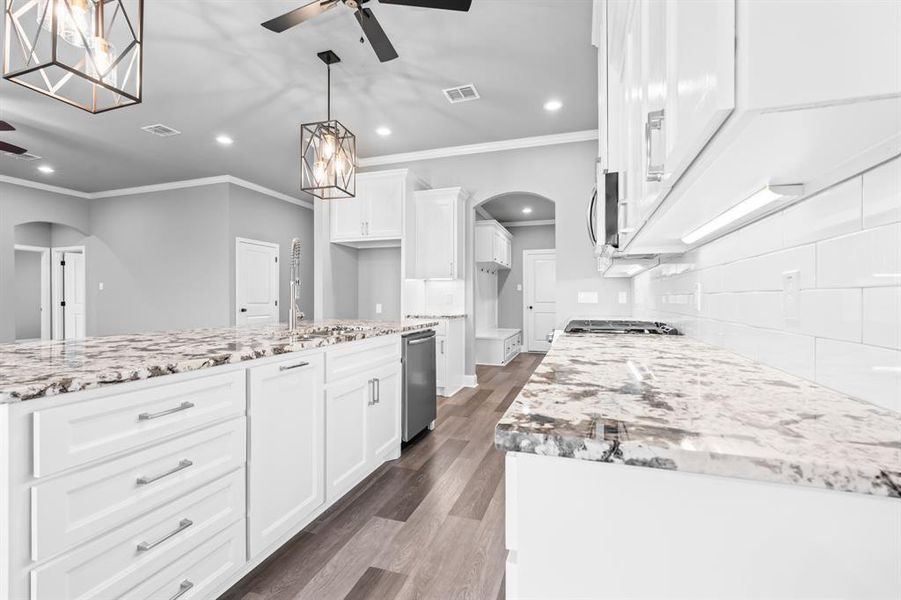 Kitchen featuring ceiling fan, ornamental molding, and arched walkways Kitchen featuring ceiling fan, ornamental molding, and arched walkways