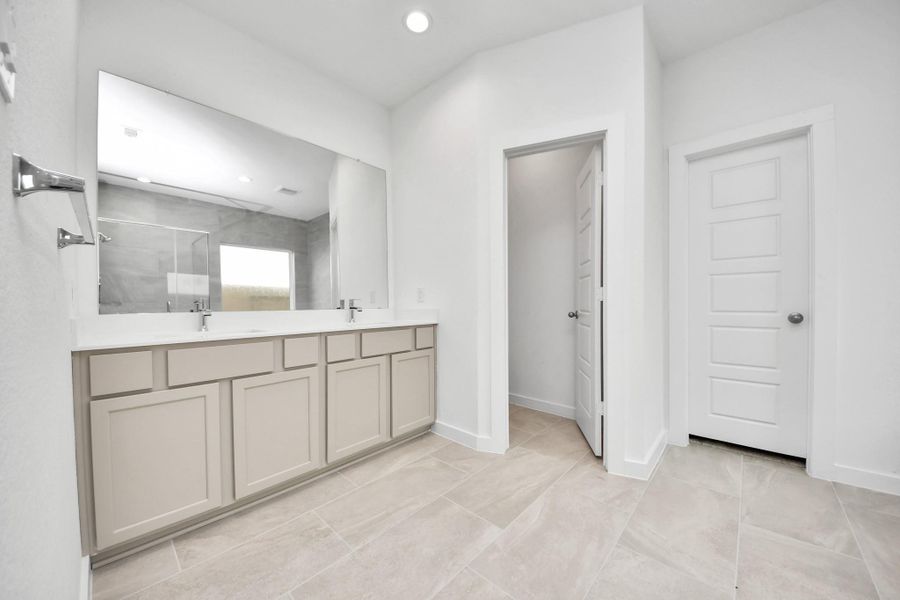 Elevate your daily routine at the elegant vanity, now equipped with double sinks, light countertops, modern hardware, and beautiful recessed lights. Sample photo of completed home with similar floor plan. Actual colors and selections may vary.