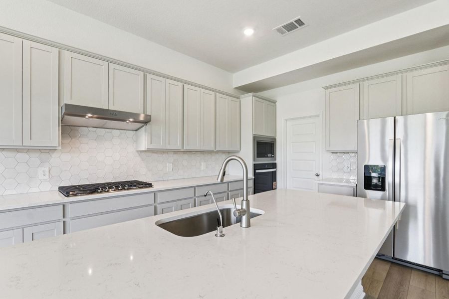 Kitchen with tasteful backsplash, appliances with stainless steel finishes, light stone counters, and recessed lighting Kitchen with tasteful backsplash, appliances with stainless steel finishes, light stone counters, and recessed lighting