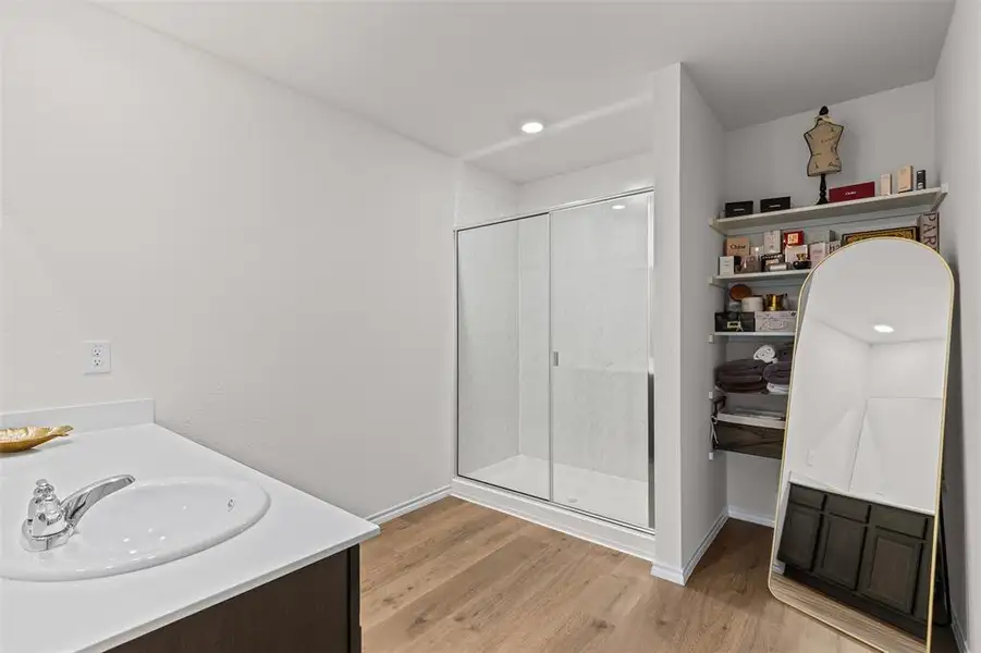 Owner's suite bath with a shower stall, vanity, light wood finished floors, and recessed lighting and tons of storage. Owner's suite bath with a shower stall, vanity, light wood finished floors, and recessed lighting and tons of storage.