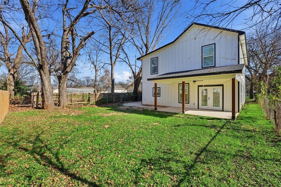 Back of property with french doors, a patio area, a fenced backyard, and board and batten siding Back of property with french doors, a patio area, a fenced backyard, and board and batten siding