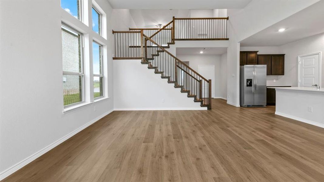 Unfurnished living room with dark wood-type flooring, a high ceiling, and recessed lighting Unfurnished living room with dark wood-type flooring, a high ceiling, and recessed lighting