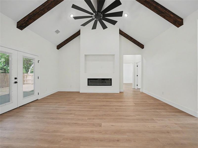 Vaulted ceiling with exposed wood beams, a modern fireplace, wood-finish flooring, and French doors Vaulted ceiling with exposed wood beams, a modern fireplace, wood-finish flooring, and French doors