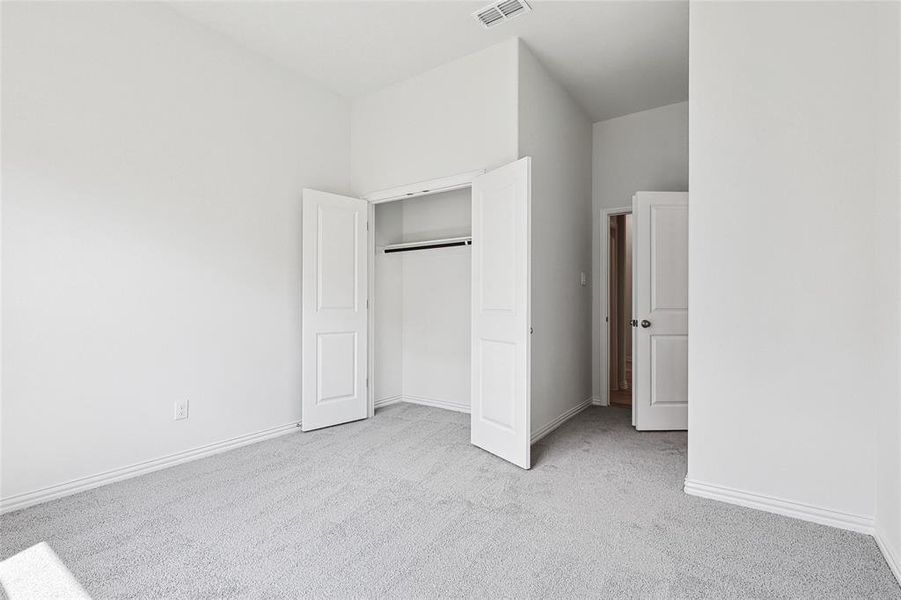 Unfurnished bedroom with a high ceiling, light colored carpet, and a closet