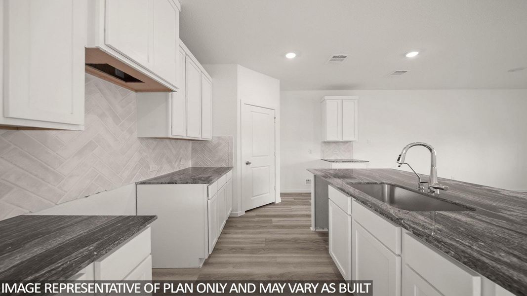 Contemporary kitchen featuring white cabinetry, dark natural stone countertops, a herringbone tile backsplash, an undermount sink with a gooseneck faucet, and wood-finish flooring