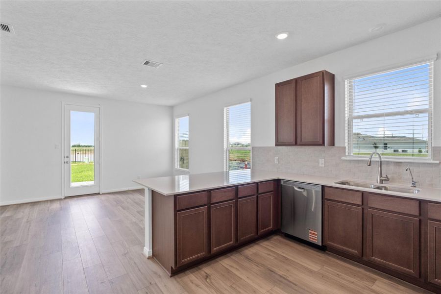 Bright kitchen featuring a sunny window over the sink, scenic backyard views, and seamless flow into the dining. Bright kitchen featuring a sunny window over the sink, scenic backyard views, and seamless flow into the dining.
