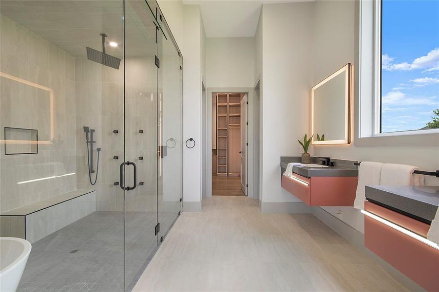 Bathroom featuring a shower stall, vanity, and a spacious closet