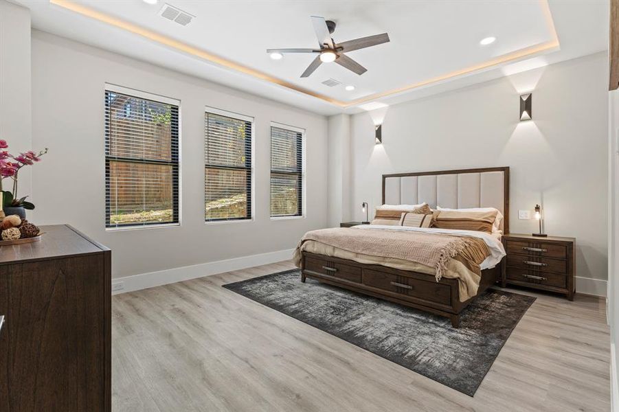 Bedroom featuring a tray ceiling, recessed lighting, a ceiling fan, and light wood finished floors