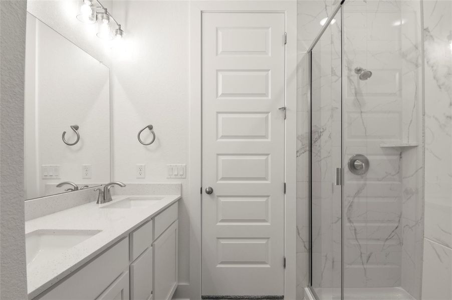 Full bathroom with a marble finish shower and double vanity