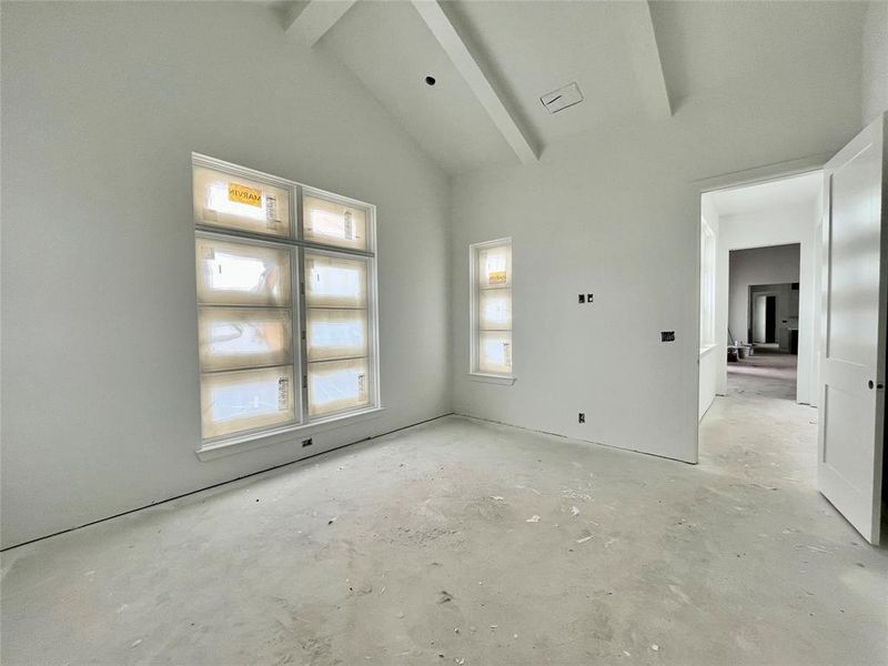 Empty room with lofted ceiling with beams