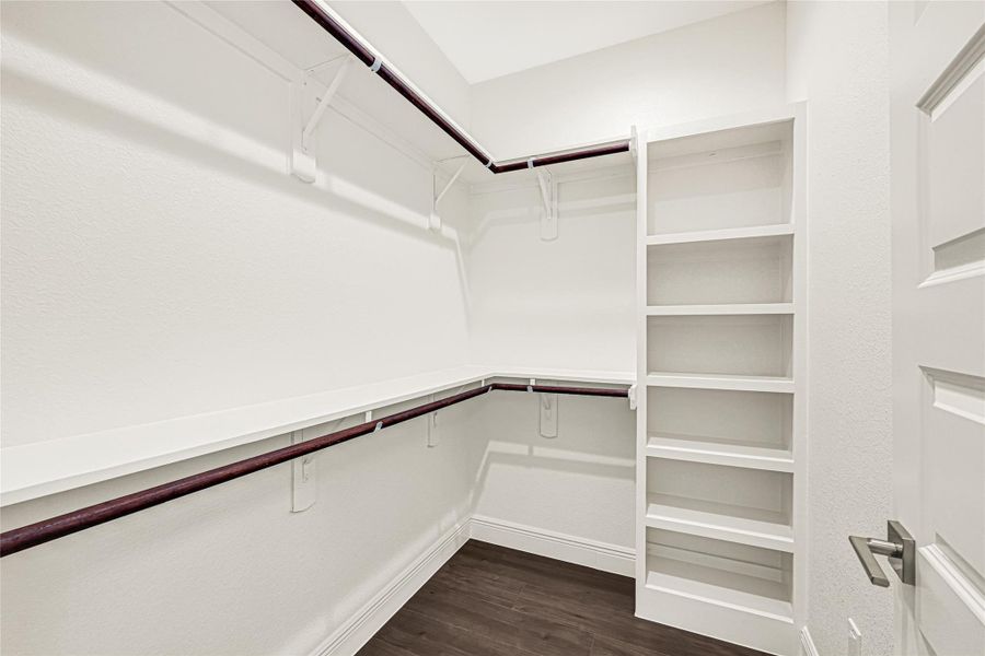 This spacious walk-in closet features sleek shelving and ample hanging space on both sides, perfect for organized storage. Its clean, bright design is complemented by dark hardwood flooring, adding a touch of elegance. This spacious walk-in closet features sleek shelving and ample hanging space on both sides, perfect for organized storage. Its clean, bright design is complemented by dark hardwood flooring, adding a touch of elegance.