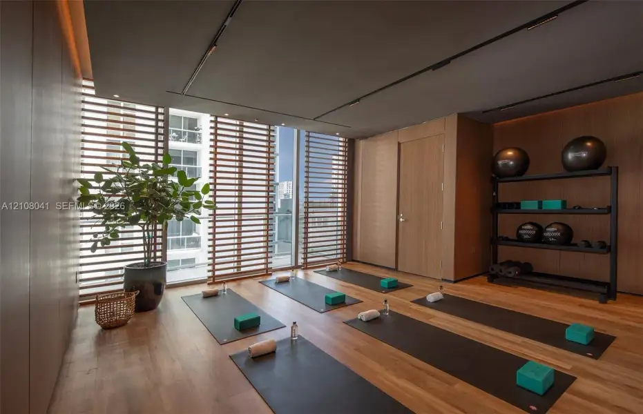 Wood-finish flooring, floor-to-ceiling windows with horizontal wood-slat privacy screens, recessed ceiling track lighting, and full-wall wood paneling