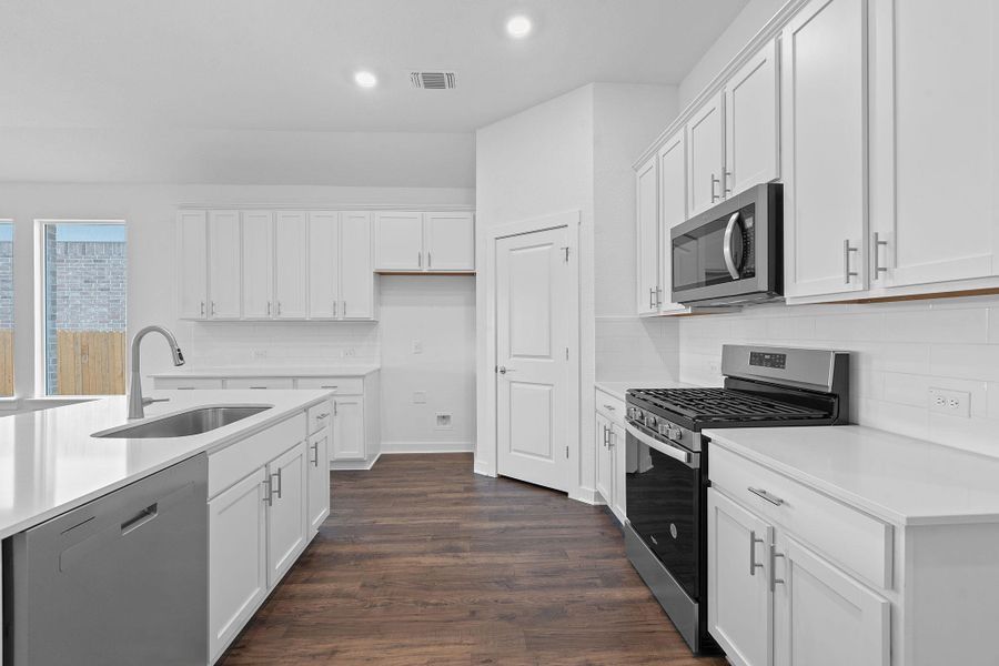 Kitchen with stainless steel appliances, white cabinets, backsplash, dark wood-type flooring, and recessed lighting Kitchen with stainless steel appliances, white cabinets, backsplash, dark wood-type flooring, and recessed lighting