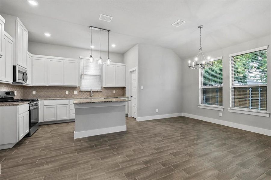 Kitchen featuring stainless steel appliances, dark hardwood / wood-style floors, white cabinets, and decorative light fixtures