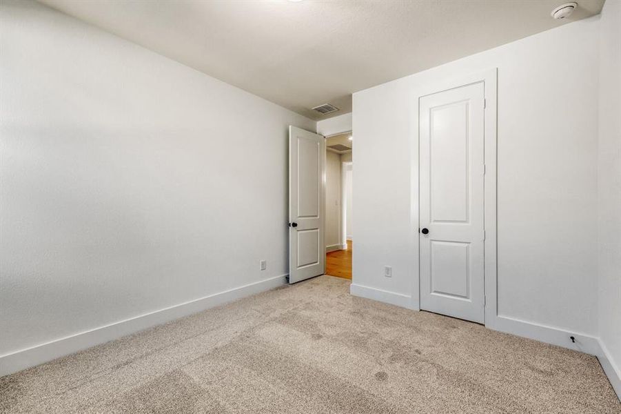 Unfurnished bedroom with light carpet and baseboards