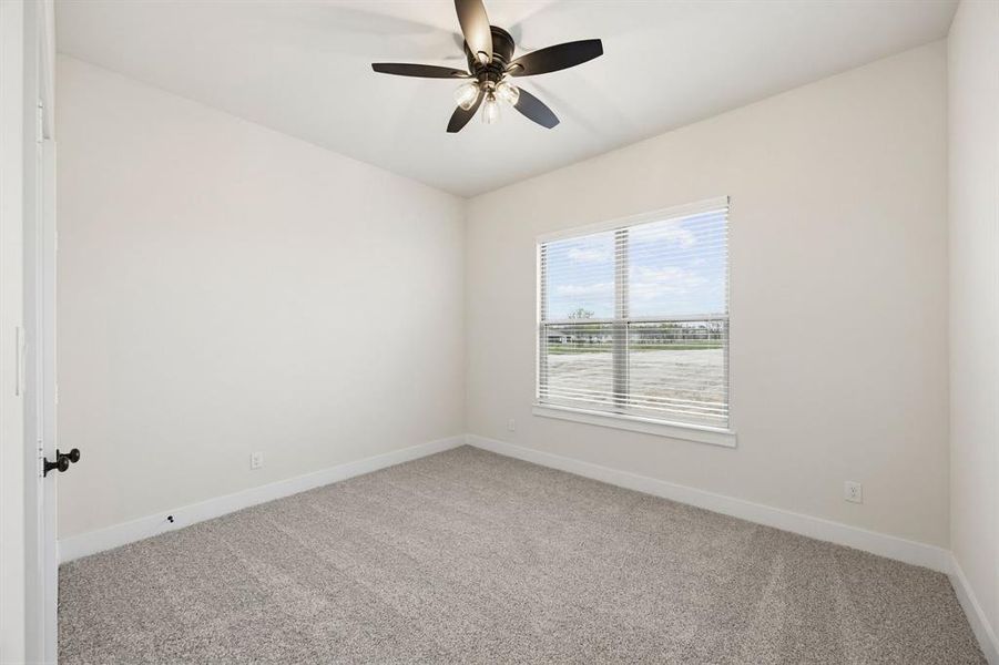 Neutral-toned room featuring a window with horizontal blinds, light gray carpet, and a ceiling fan with integrated lighting