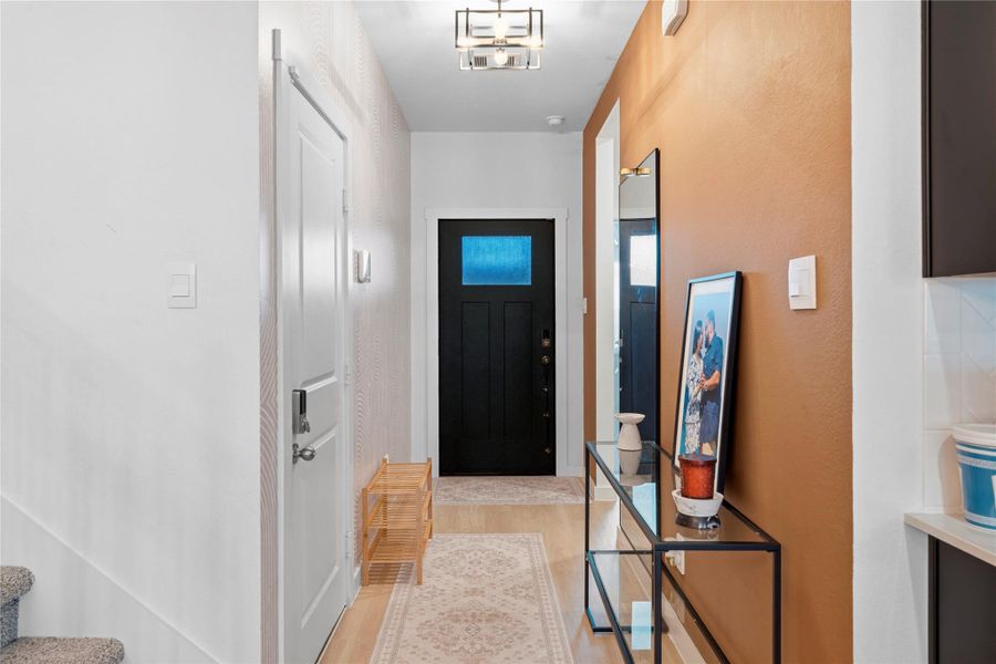 A bright foyer showcases a bold dark entry door, textured accent wall, and beautiful wood-look flooring. A bright foyer showcases a bold dark entry door, textured accent wall, and beautiful wood-look flooring.
