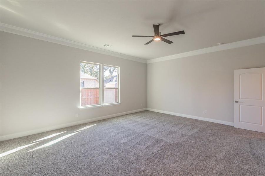 Spare room featuring light carpet, ceiling fan, and crown molding