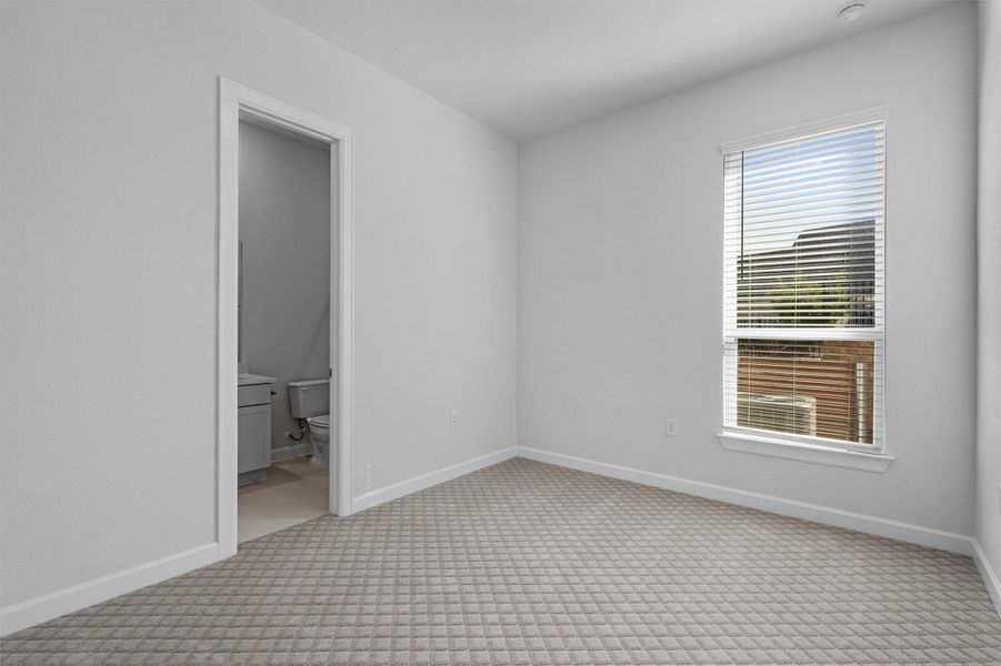 Unfurnished bedroom featuring light colored carpet and connected bathroom Unfurnished bedroom featuring light colored carpet and connected bathroom