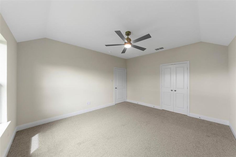 Spacious room featuring vaulted ceilings and neutral-toned carpeting