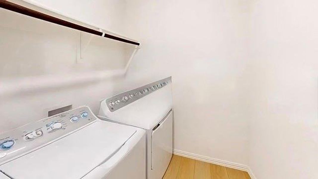 Washroom with washer and dryer and light wood-style floors